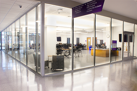 A view looking through the large all-glass walls at students at work in the Chevron Center for Engineering Education