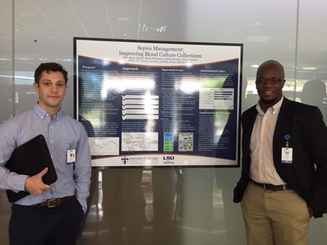 Two students posing with project board about sepsis management