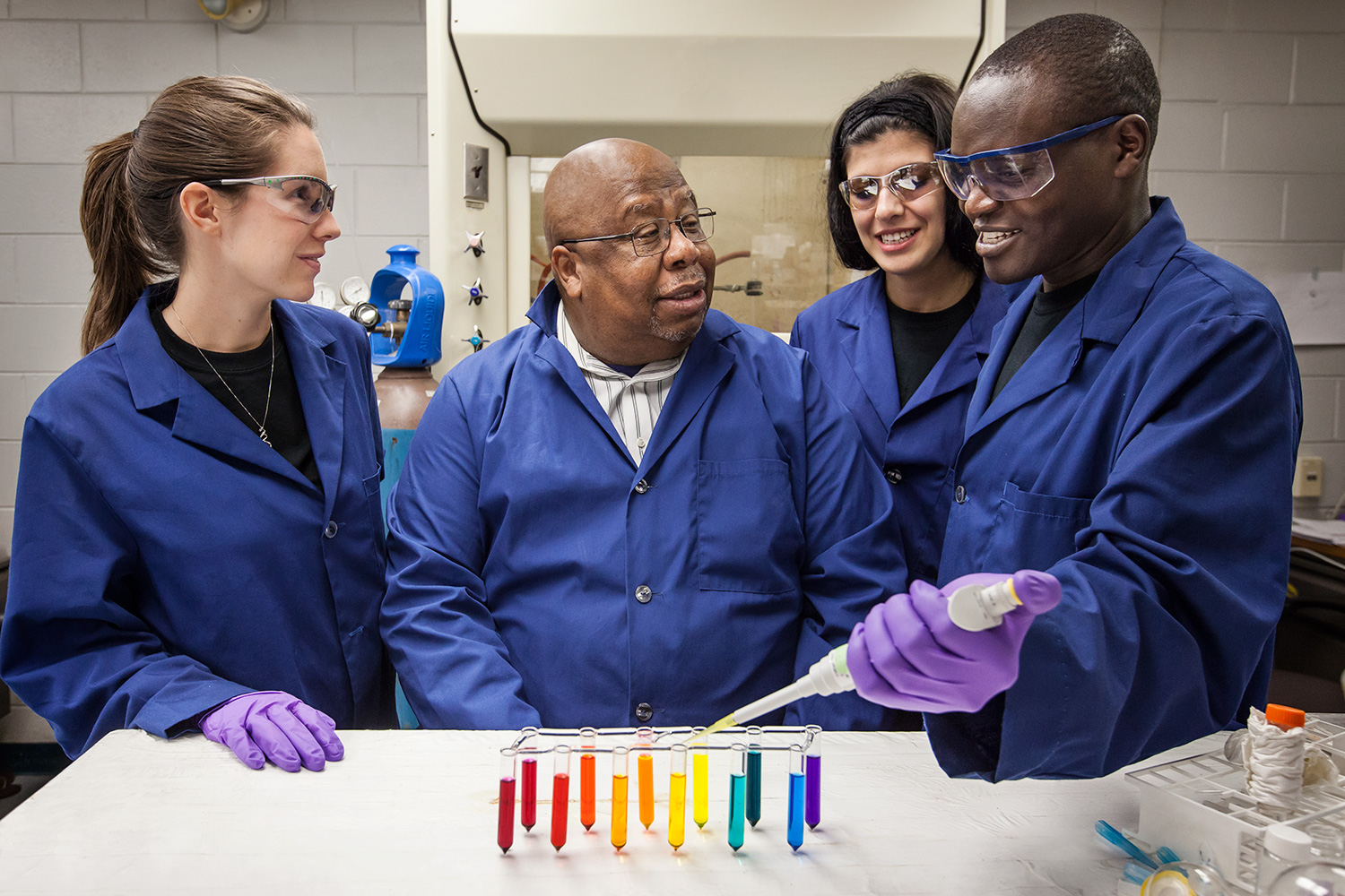 Dr. Warner at a lab table surrounded by some of his students.