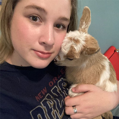 Hannah holds a young goat. 
