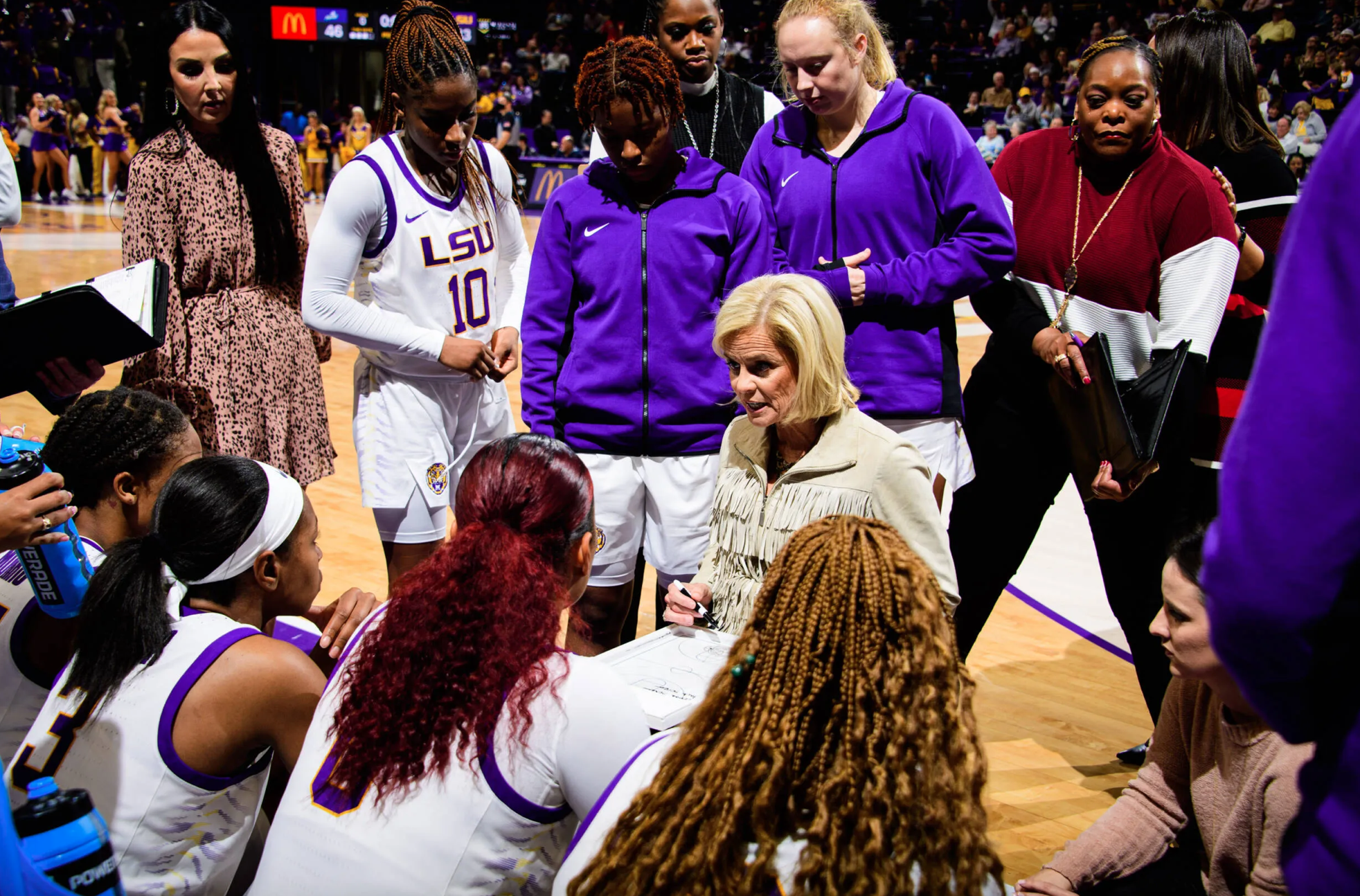 Coach Kim Mulkey huddles with her team and draws up a play.