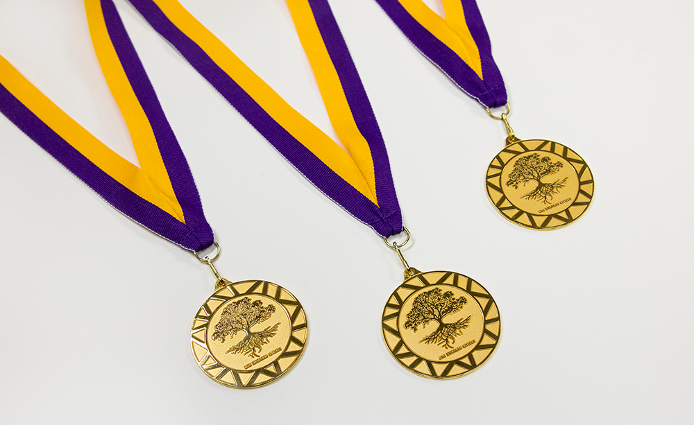 gold medal on purple and gold ribbon lies on table