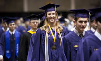 student in cap and gown at graduation with a Distinguished Communicator medal