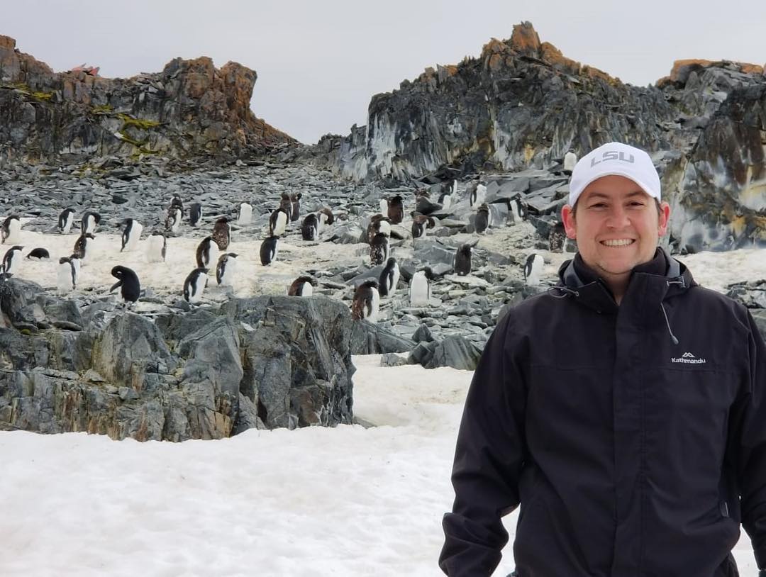 researcher Mike Polito in Antarctica standing in front of penguins