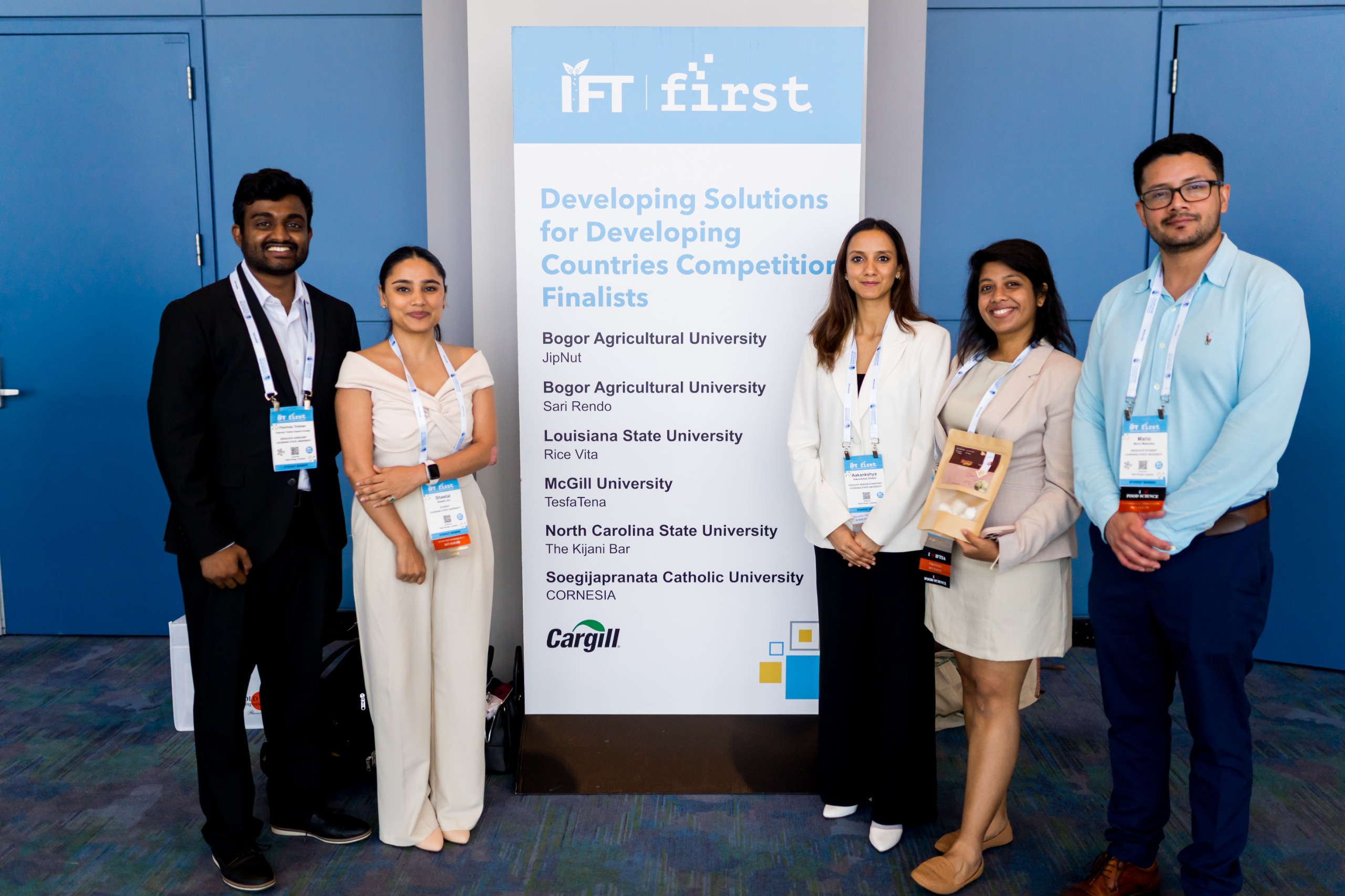 students posting in front a banner.