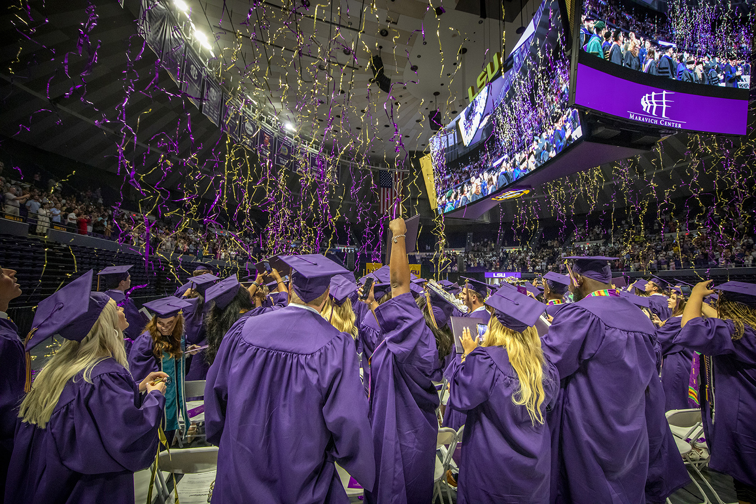 Graduates celebrate amid purple and gold streamers during LSU's summer commencement
