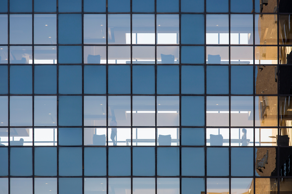 Exterior of building windows showing office environment inside.