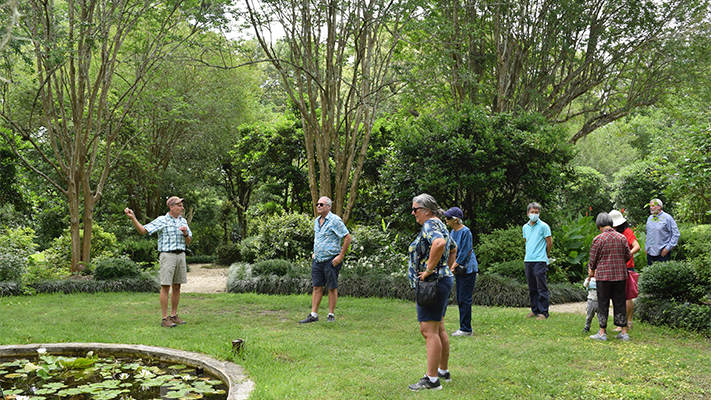group of people listen to speaker giving a tour of a garden