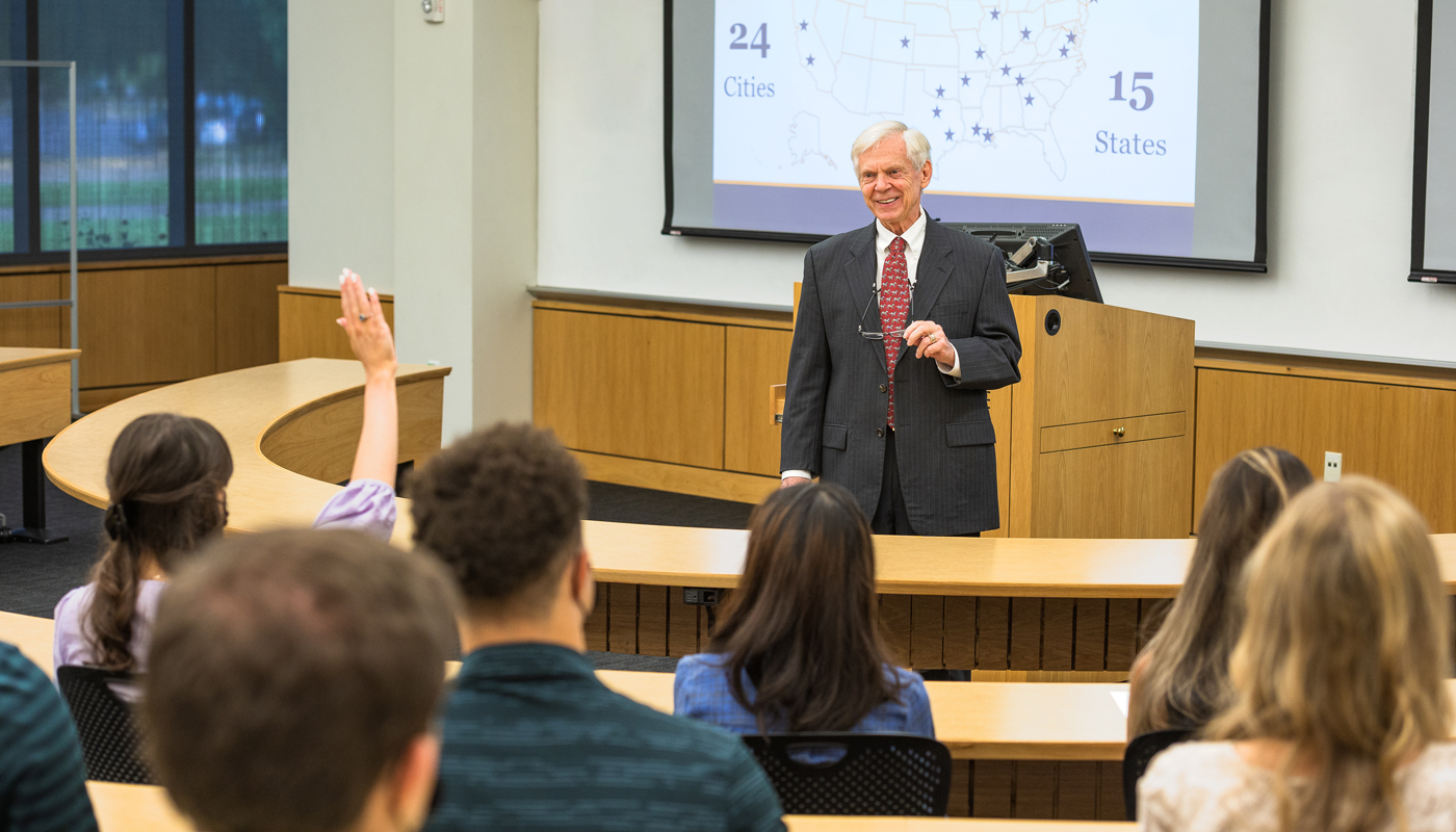 Professor Glenn Sumners, LSUCIA&CRM director, speaks to a class. One student raises her hand with a question. 