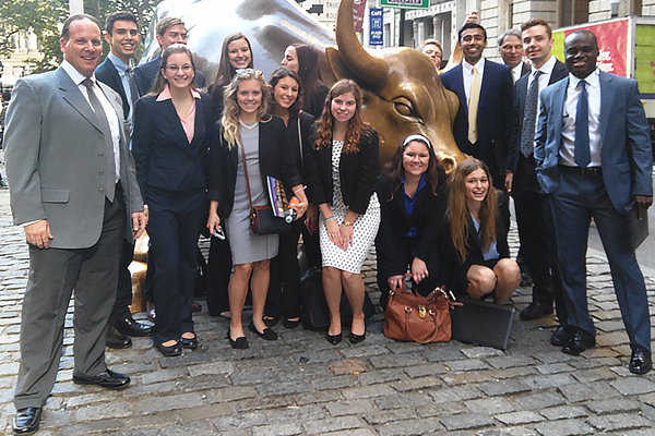Students stand in front of bull on Wall Street in NYC