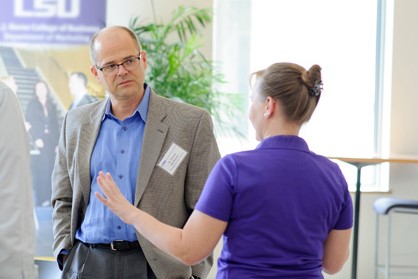 Thomas Greckhamer talks with student in purple shirt. 
