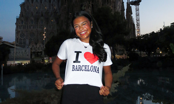 Cate Warren wears an I love Barecelona shirt and stands in front of Basilica of the Sagrada Familia.
