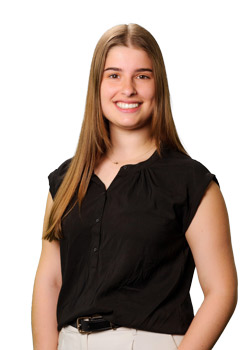 Abigail Soudelier headshot against a white background. She wears white slacks and a black shirt.
