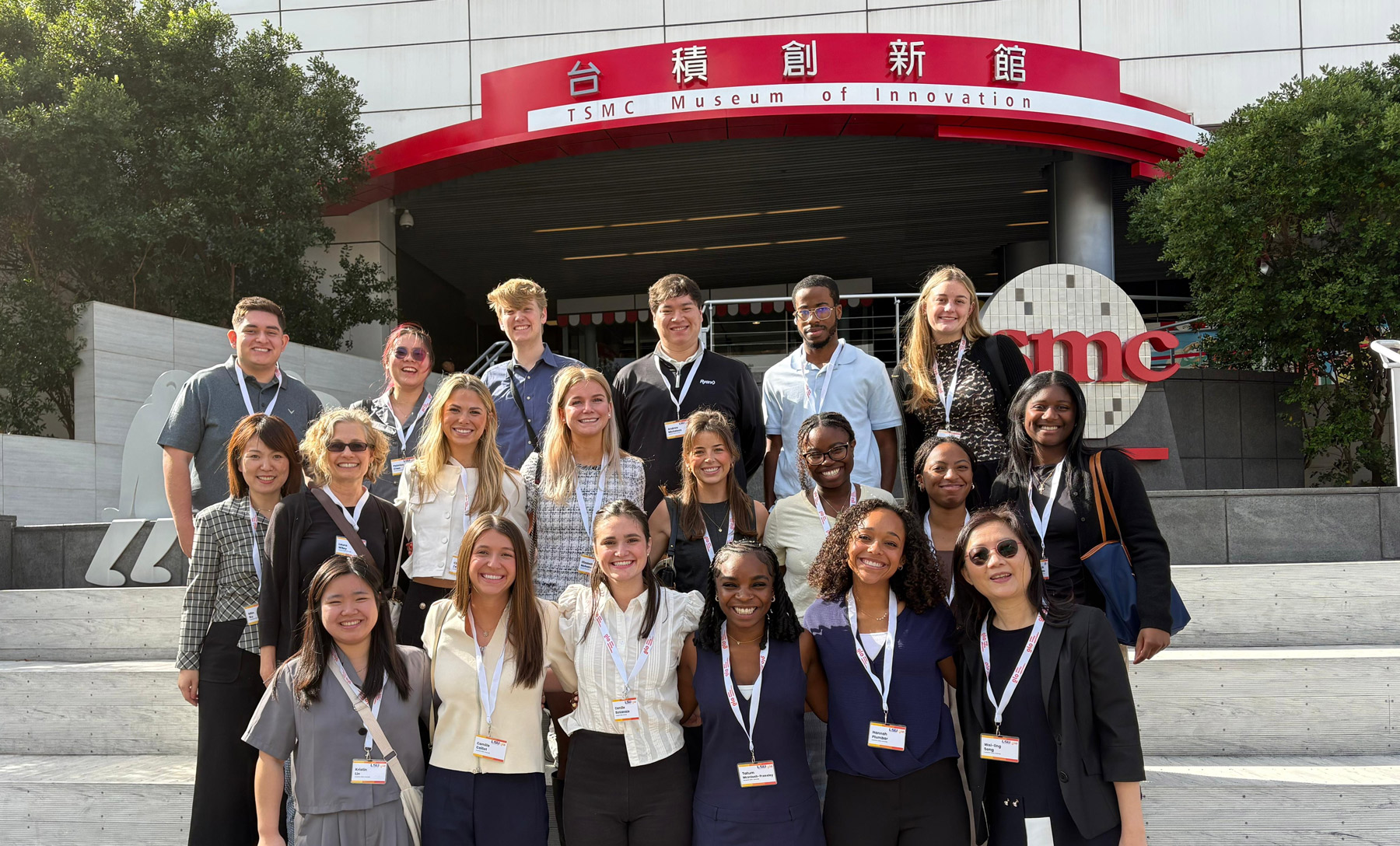Group photo of LSU students, faculty, and local guides outside an innovation museum in Taiwan. They wear business attire and smile broadly.