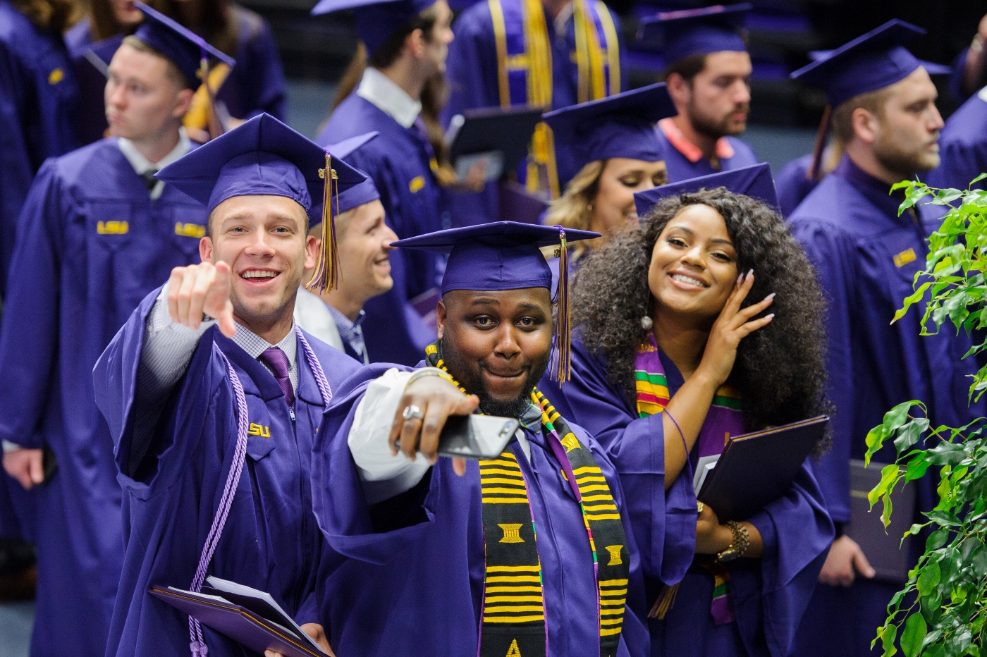 Graduates smiling and pointing at camera