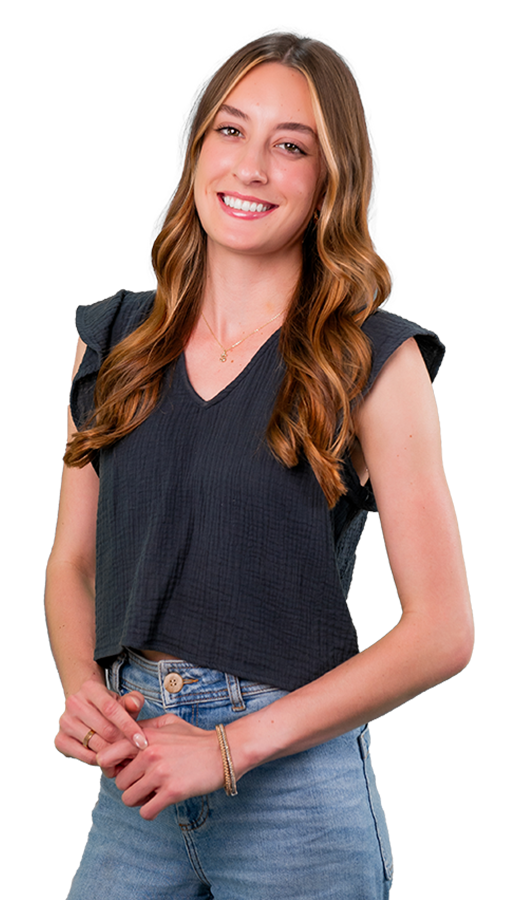 Sveyna Stoyanoff wears a black linen shirt with fluttery sleeves with light jeans. Her hands are crossed in front of her body. She smiles.