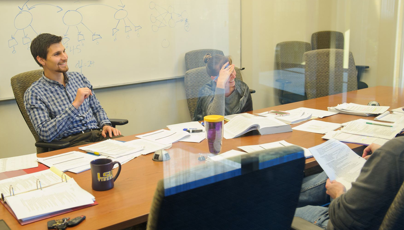 PhD students working in conference room with books. 