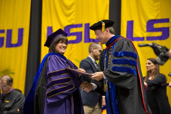 President F. King Alexander hands a graduate her diploma at commencement 