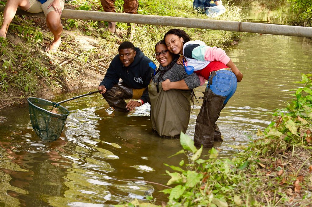 Three students standing in hip-deep water during research as part of the Environmentors Program.