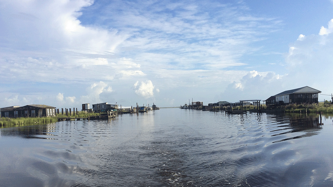 an image of the wake of a boat and houses on the delta