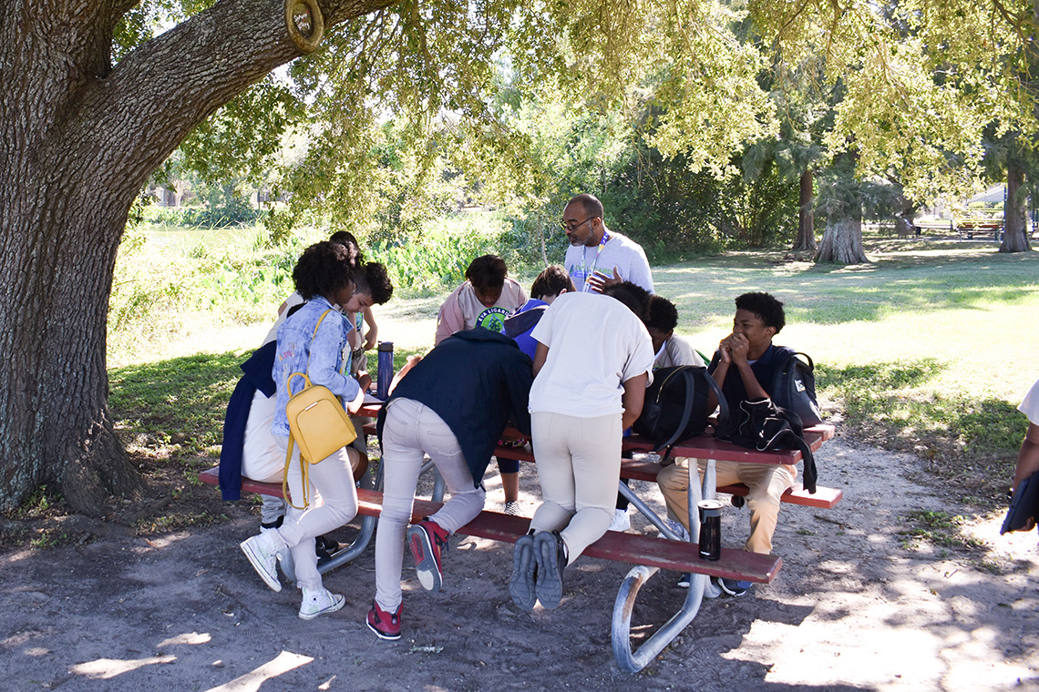 An environmental sciences teacher talks to students underneath a treee