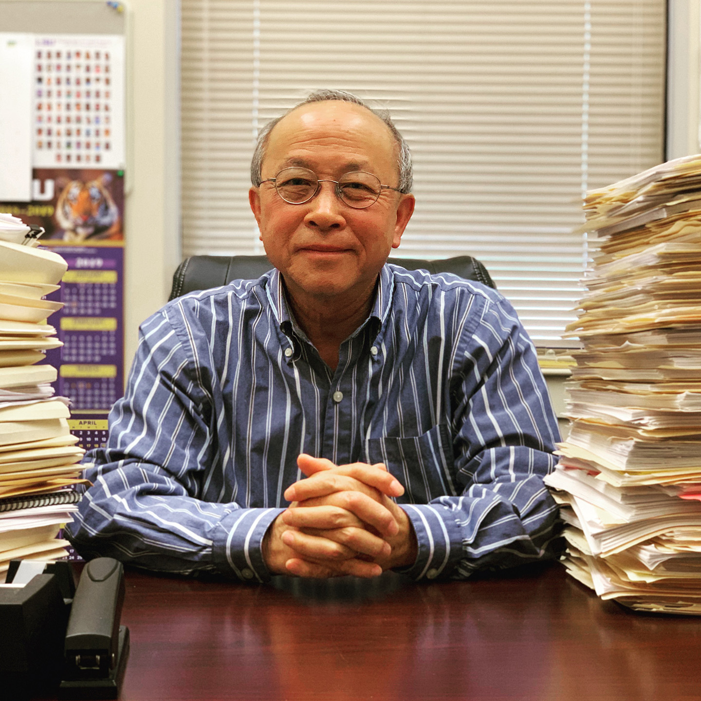 Kam-biu Liu at his desk with stacks of papers