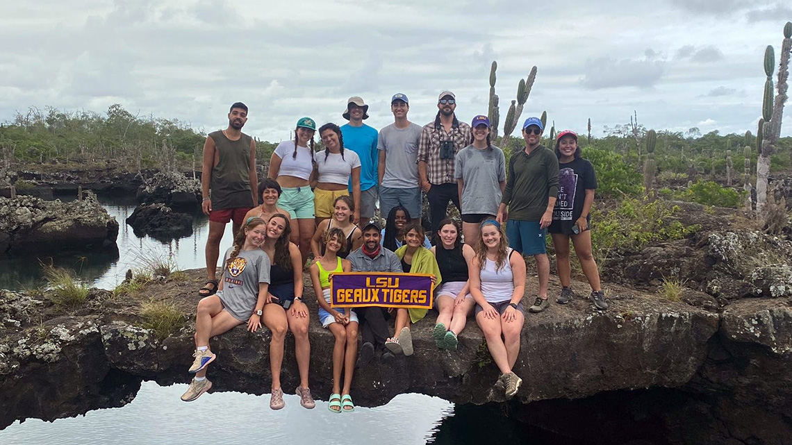A group of Coastal Environmental Science and biology students stand on a bridge with their professors