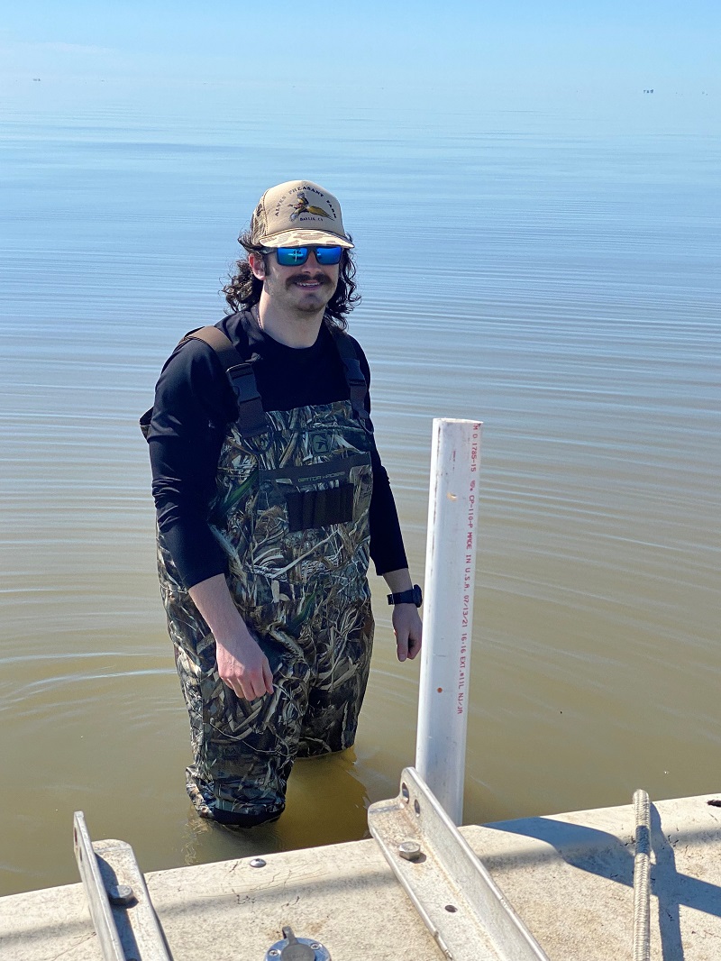 Jacob Reinhardt in waders in knee-high water in Wax Lake Delta