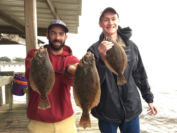 two men pose with flounders
