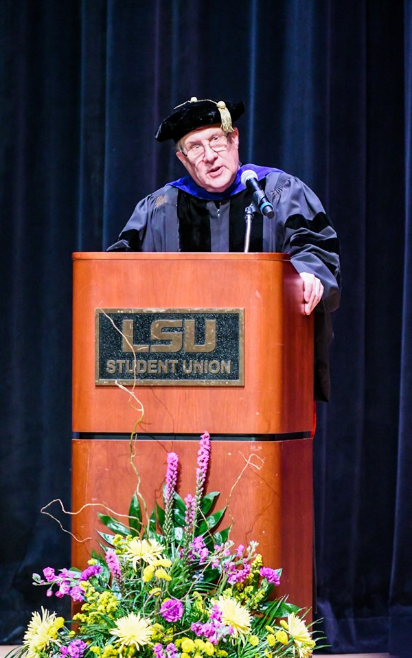 A man stands speaks from behind a podium