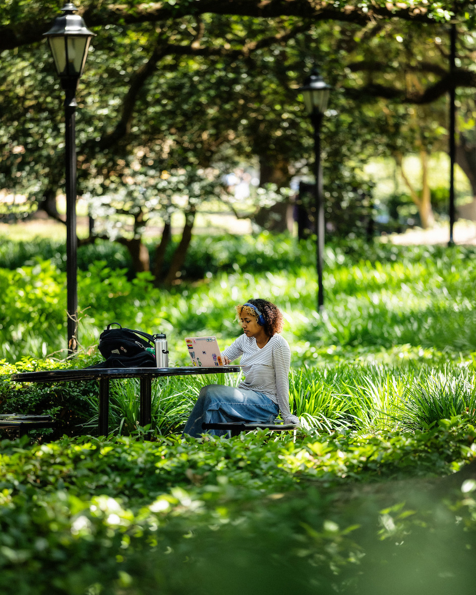 A student in the woods with a laptop