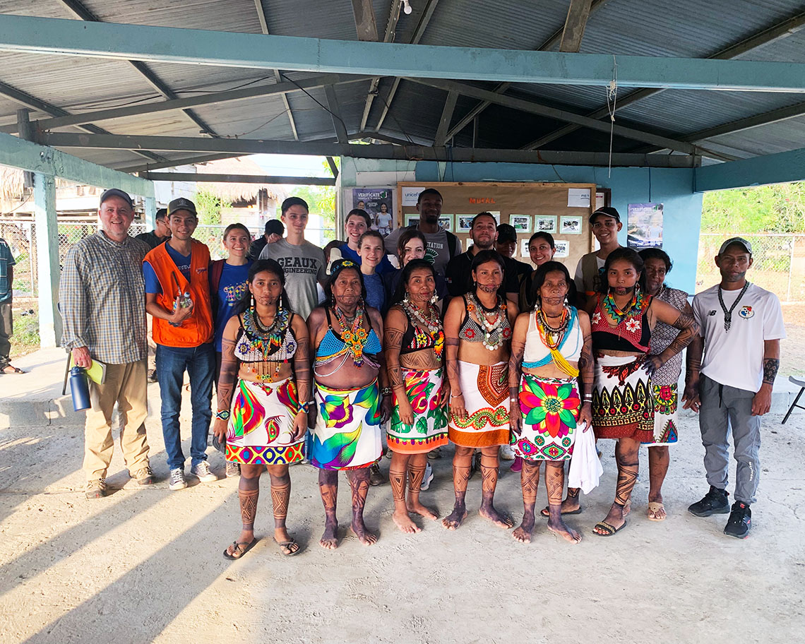 a group of students and native Panamanians stand together and smile