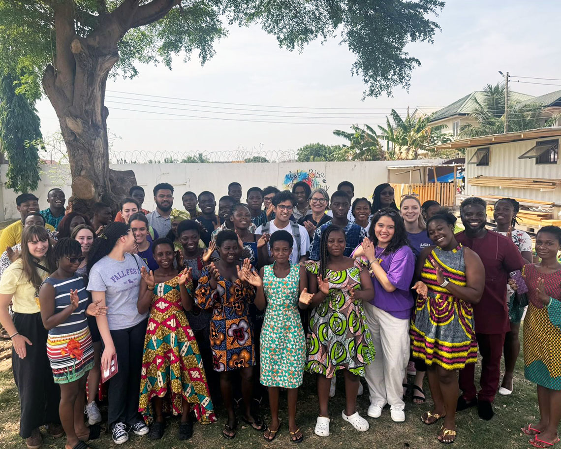 A group of people in Ghana stand outside and smile