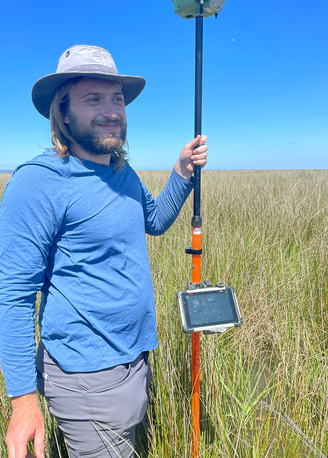  a man stands in the marsh with a pole