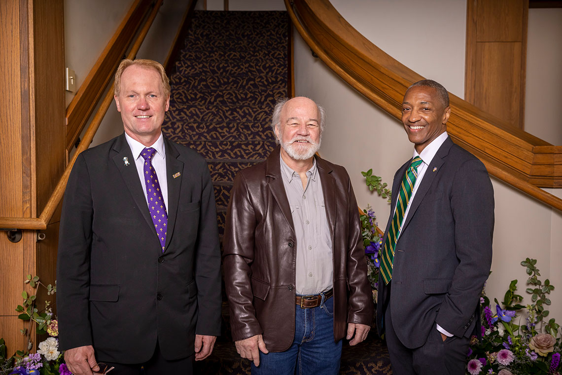 three men stand in front of a staircase