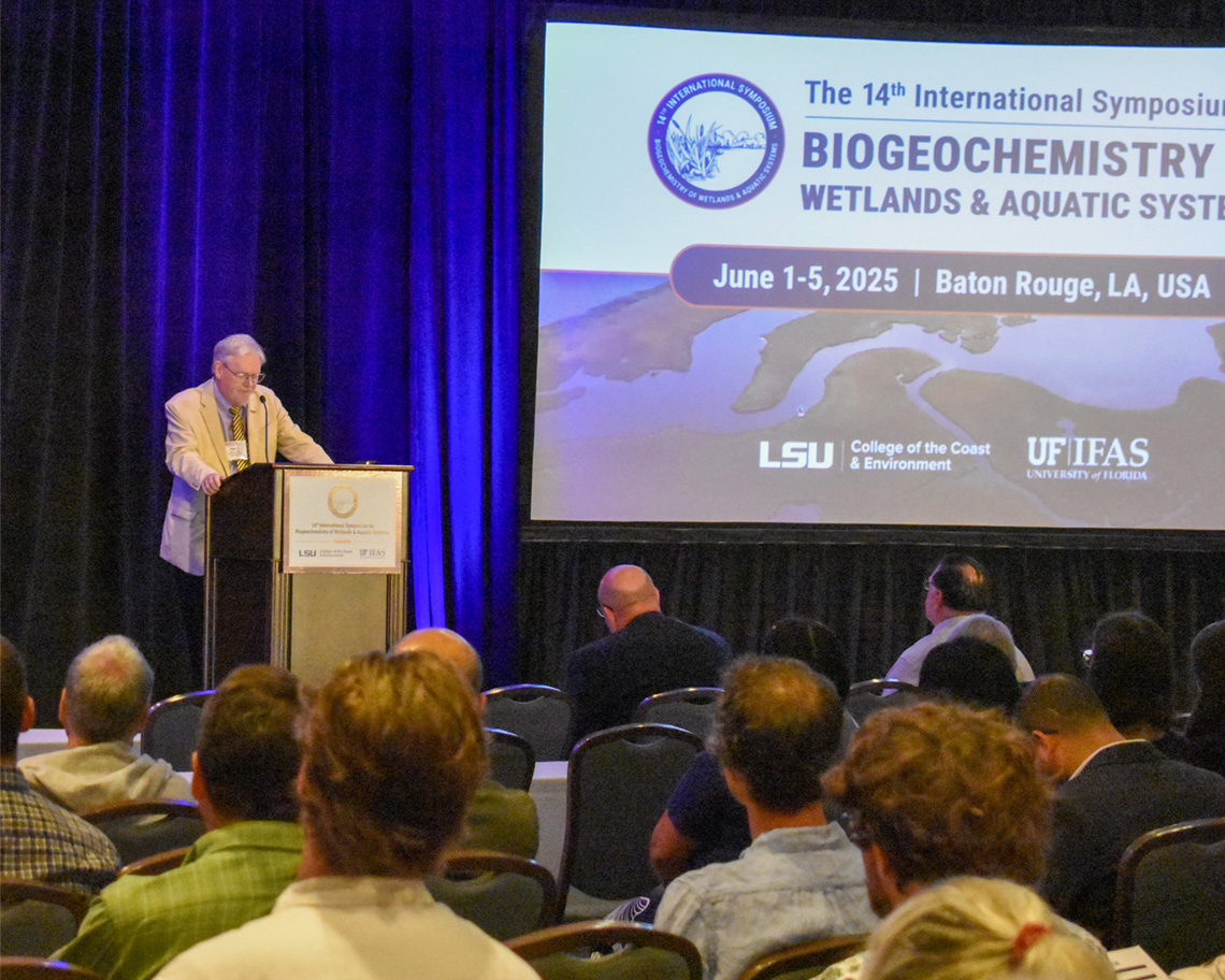 A man stands at a podium in front of a powerpoint