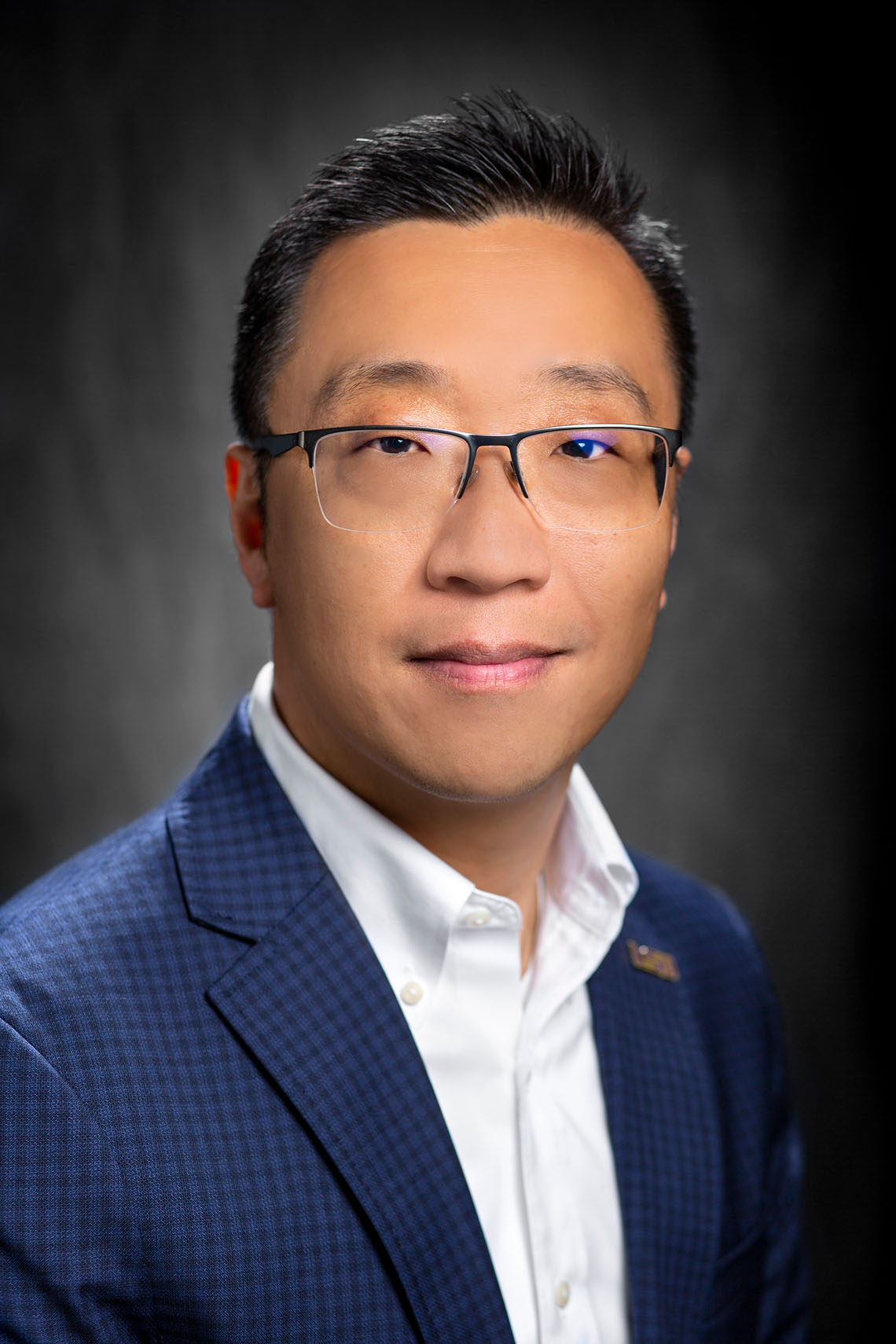 A portrait of a man wearing a blazer smiling at the camera