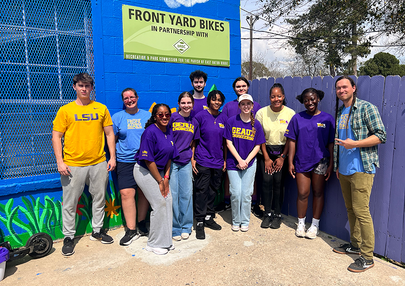 group of LSU students and community member pose outside of building