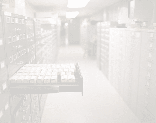 A long hallway lined with rows of filing cabinets and drawers, with one drawer open revealing organized index cards. Description generated by AI