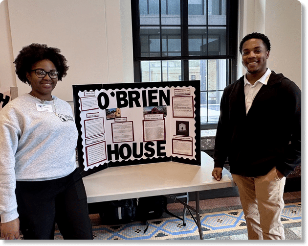 A bulletin board displays information about O'Brien House with sections on SMART goals, federal and local policies, services offered, populations served, and interventions utilized. Description generated by AI