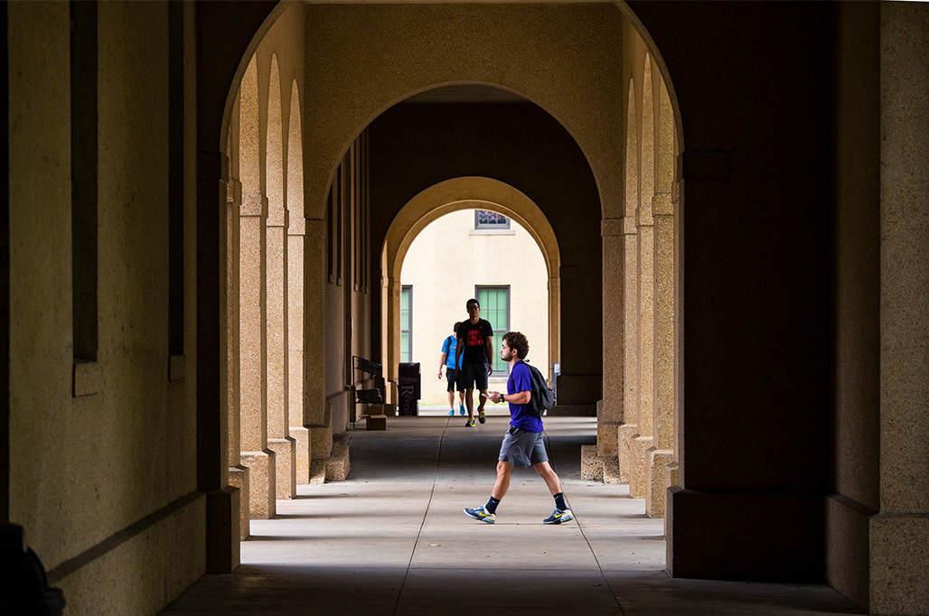 students walking under arches on campus