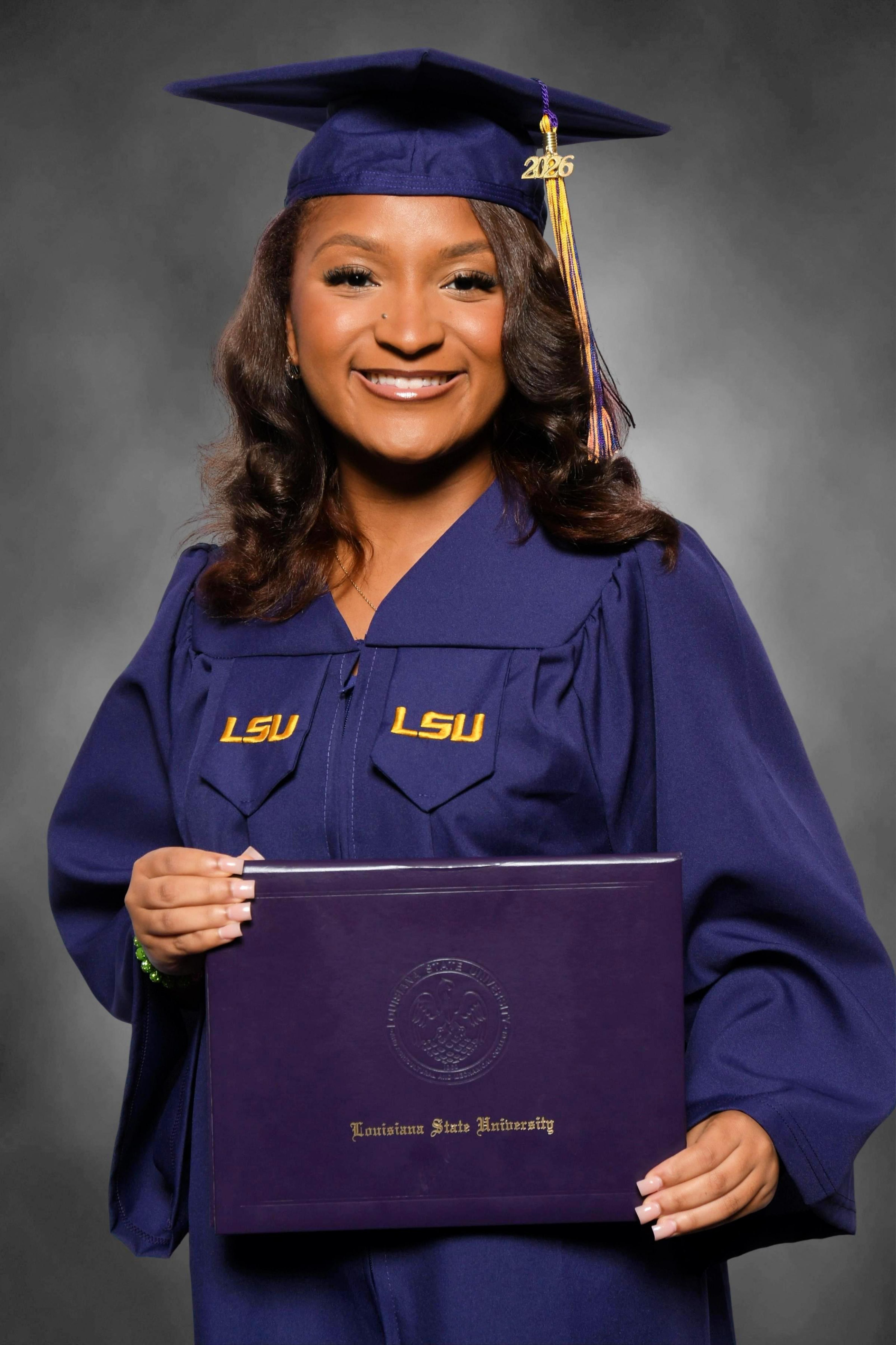 Paris Bickham wearing LSU graduation regalia holding and LSU diploma cover