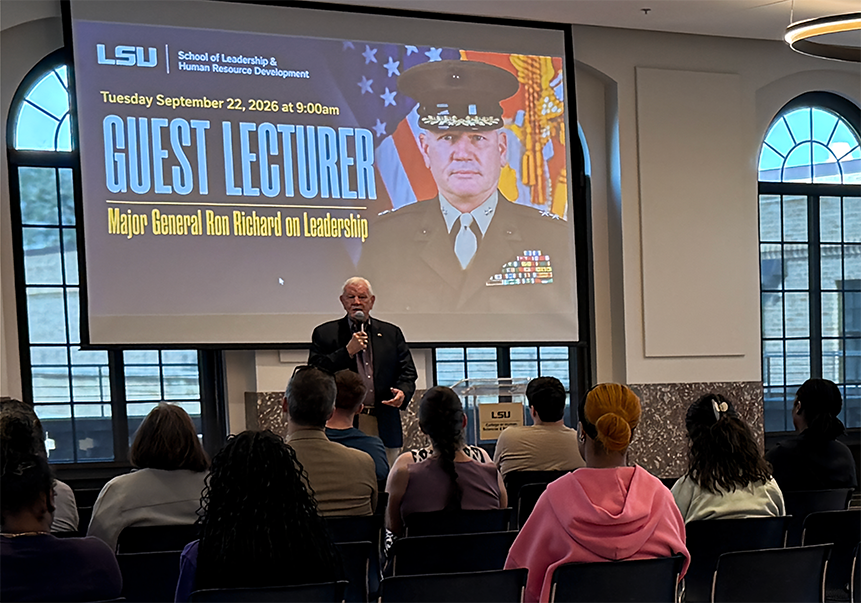 Maj. Gen. Ron Richard, USMC (Ret.), speaks to students in the Huey P. Long Fieldhouse Ballroom. A screen behind him reads "LSU School of Leadership & Human Resource Development, Tuesday September 22, 2026 at 9:00am, Guest Lecturer: Major General Ron Richard on Leadership."