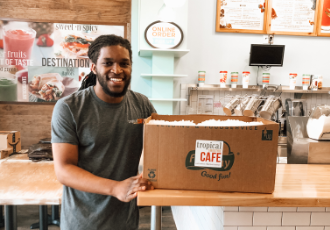 Tropical Smoothie Cafe employee with boxed donation.