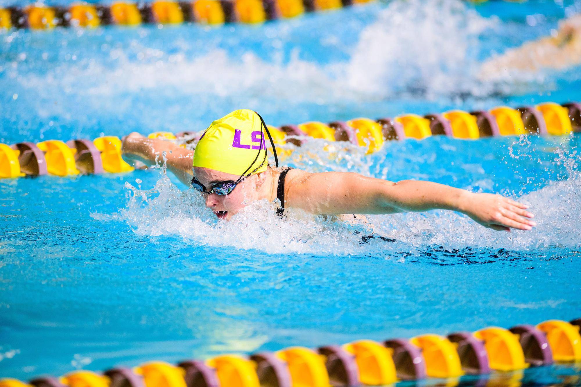 Helen Grossman swimming with her head down with an LSU swim cap and goggles on