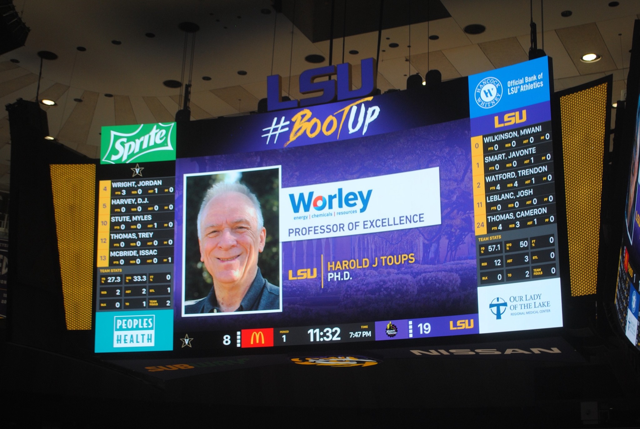 Scoreboard display with photo of Dr. Harry Toups and announcement of award