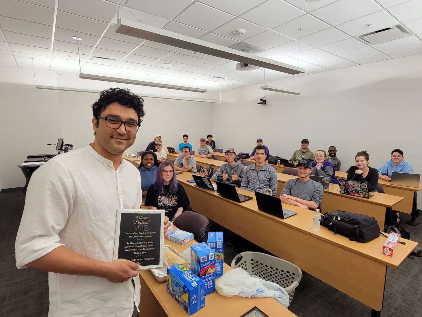 Dr. Kargarian holding up his Outstanding Professor award next to his students.