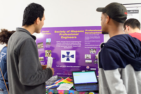 Students gather around a poster for the Society of Hispanic Professional Engineers