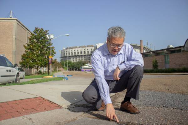 Guoqiang pointing to cracks in the road at LSU