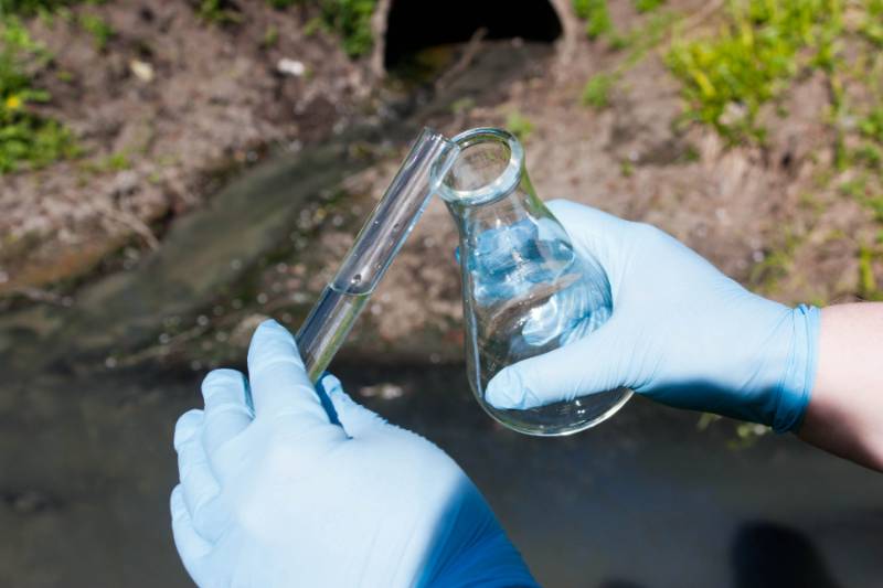 Image of researcher taking samples of wastewater.